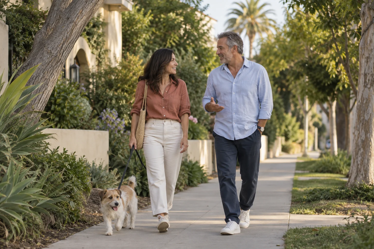 Two friends walking a dog on a leafy sidewalk